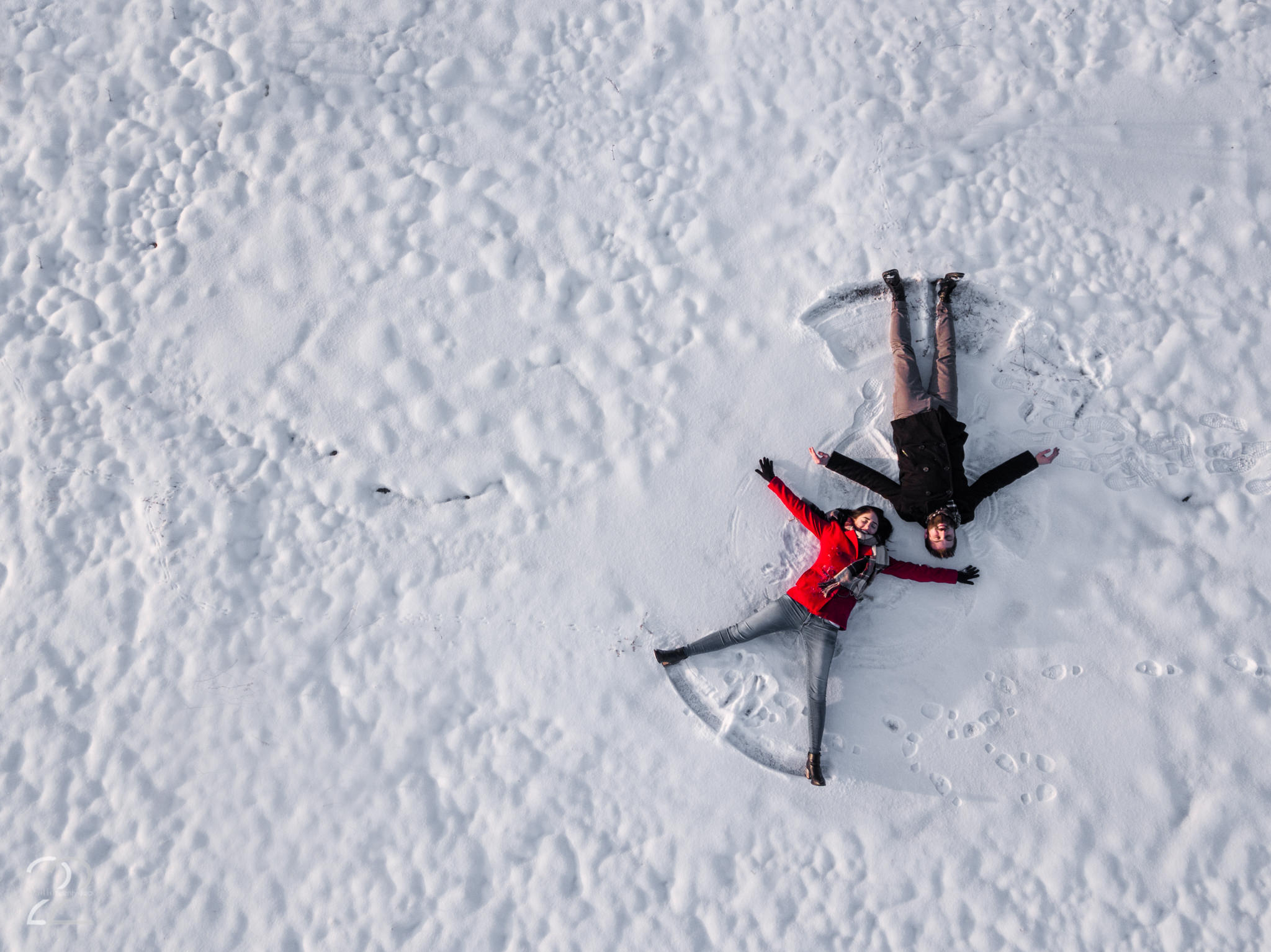 A man and woman make snow angels at Oakes Quarry Park by Dayton Wedding Photographer Studio 22 Photography